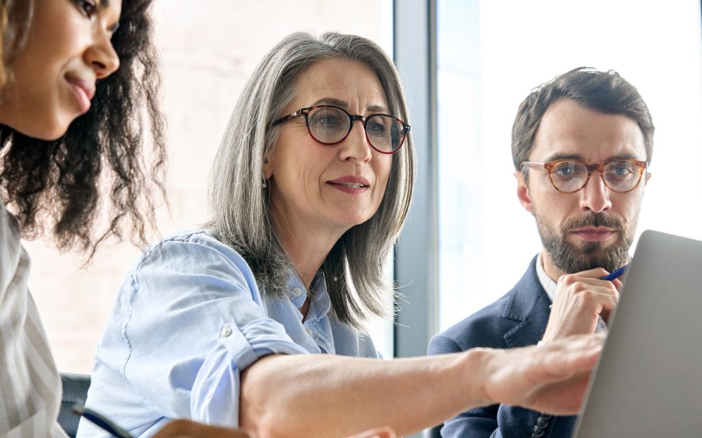 Three people looking at a computer screen together.